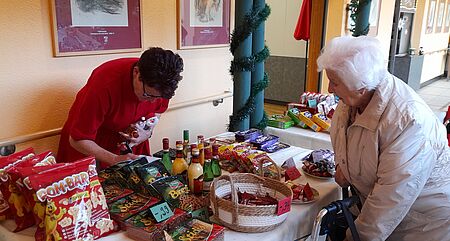 Seniorin steht vor weihnachtlich geschmückten Stand mit Süßigkeiten