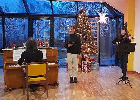 Musiker-Trio am Klavier, an der Geige und am Mikrofon