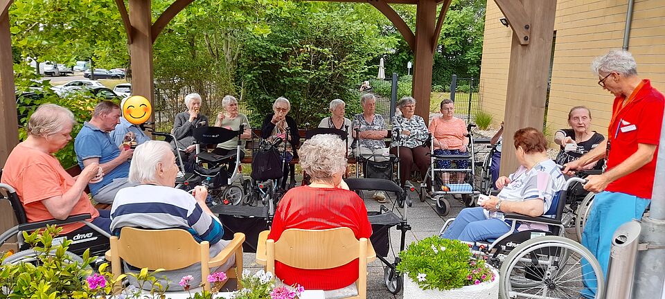 Senioren und Seniorinnen sitzen im Außenbereich zusammen und genießen ihr Eis