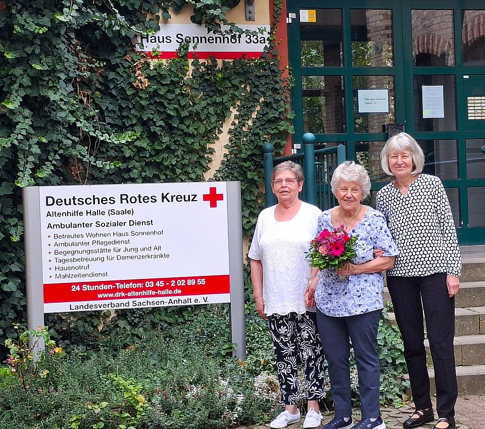 Danke Christa 3 Frauen stehen vor Gebäude "Haus Sonnenhof", die Frau in der Mitte hält Blumenstrauß in der Hand