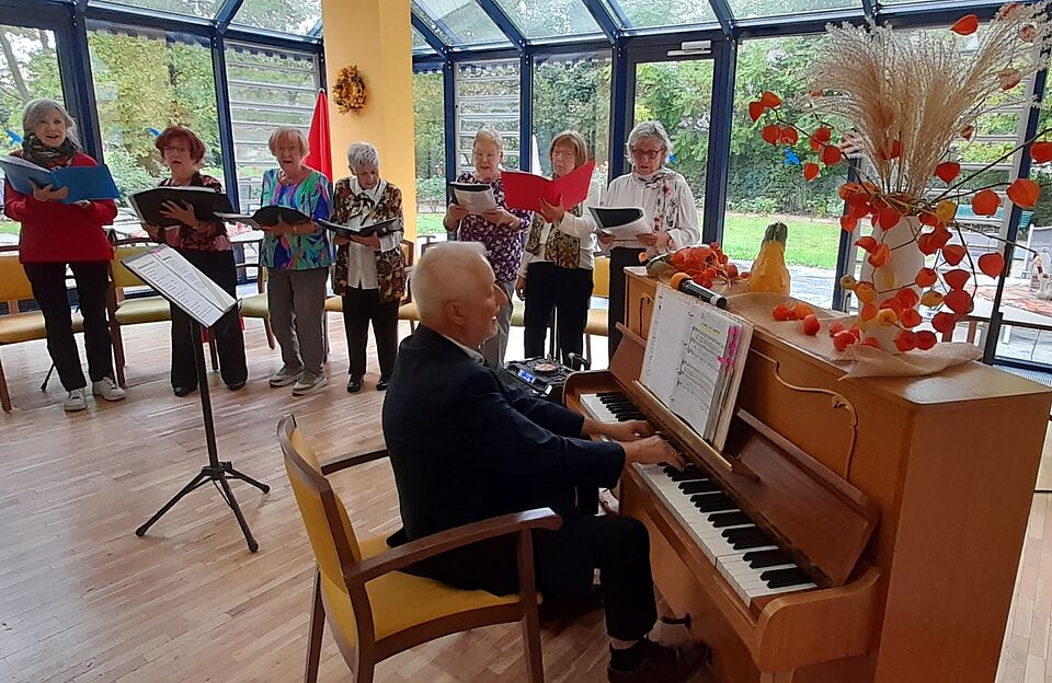 Im Vordergrund Mann am Klavier, im Hintergrund Sängerinnen