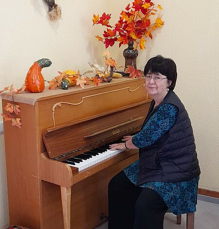 Frau am Klavier, schaut in Kamera