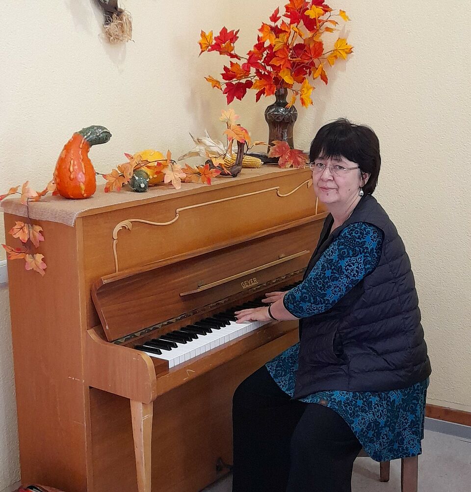 Frau am Klavier, schaut in Kamera