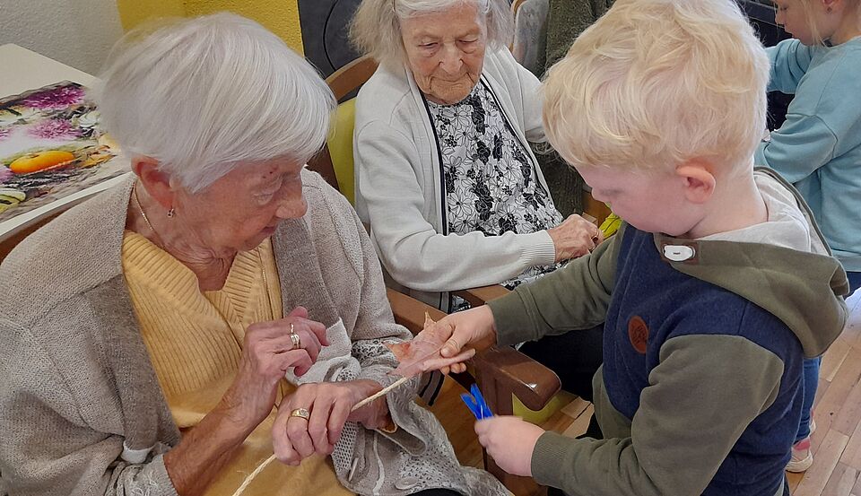 Kitabesuch Seniorin und Junge basteln herbstlich mit Blättern