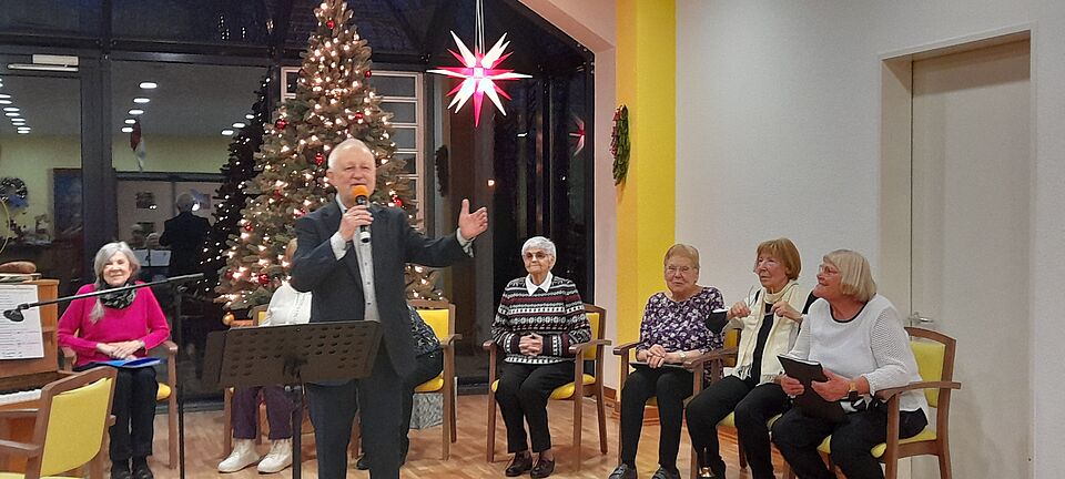 Sänger mit Mikrofon vor festlch geschmücktem Weihnachtsbaum