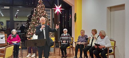 Sänger mit Mikrofon vor festlch geschmücktem Weihnachtsbaum
